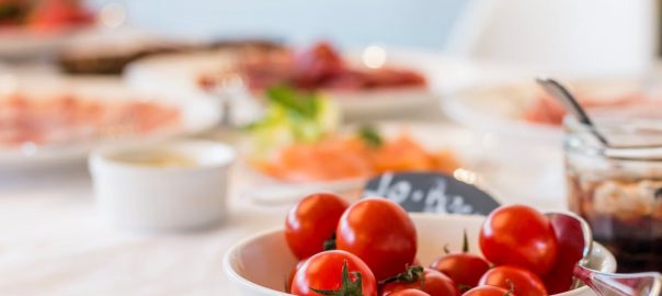 Close-up shot of vibrant cherry tomatoes in a bowl on a well-set dining table.