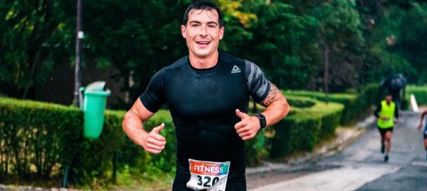 A fit male runner participating in an outdoor marathon during rainy conditions.